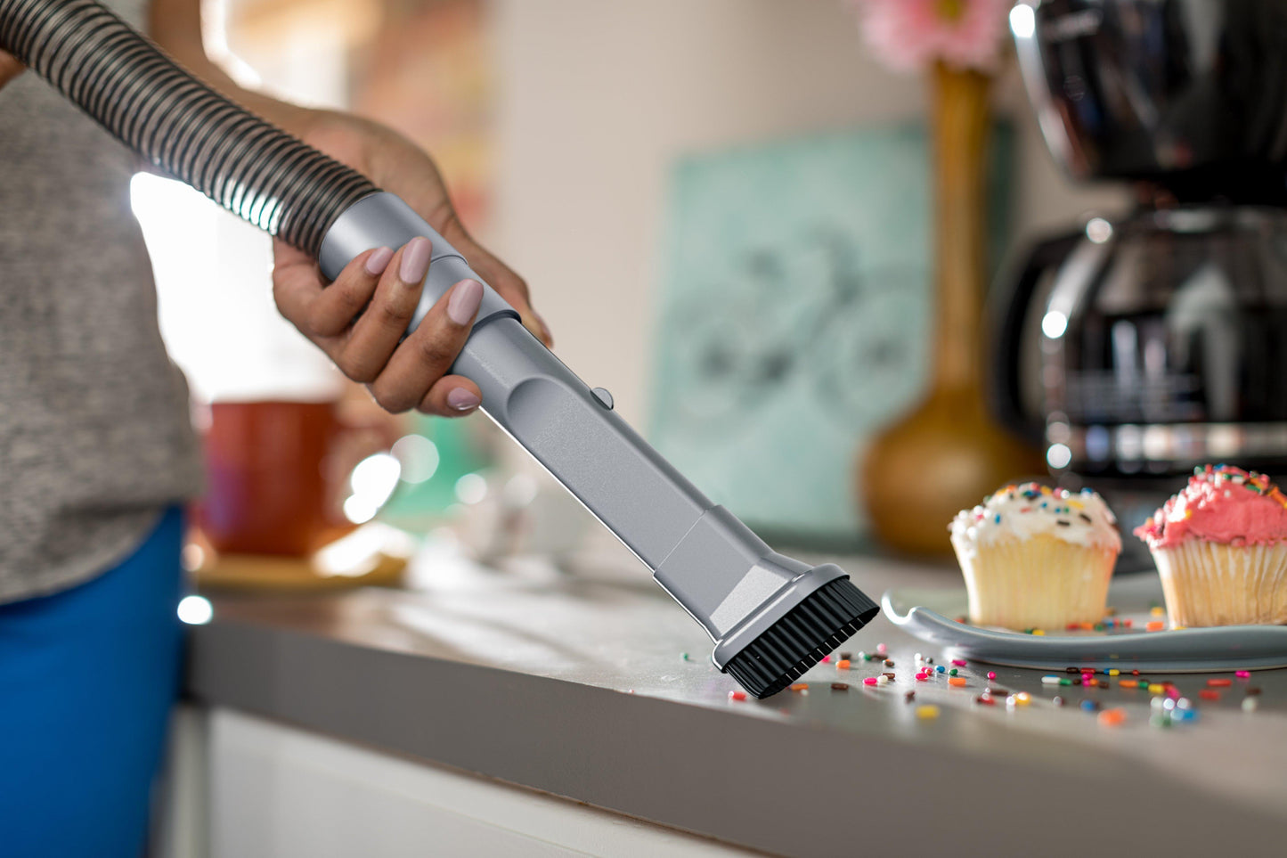 A woman cleans up spilled sprinkles with her silver vacuum attachment